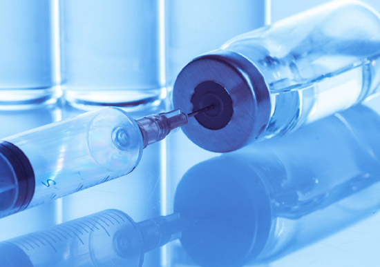Glass medicine vials filled with clear liquid all in a ring on a shining chrome surface